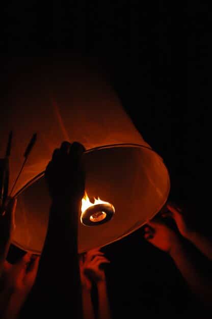 A person playing a large gong, with mallets in hand, standing in a dimly lit room, creating a dramatic and immersive atmosphere, emphasizing the powerful sound waves emanating from the gong.