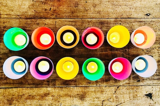 Close-up shot of various colored candles arranged in a circle, each candle emitting a distinct and vibrant light.